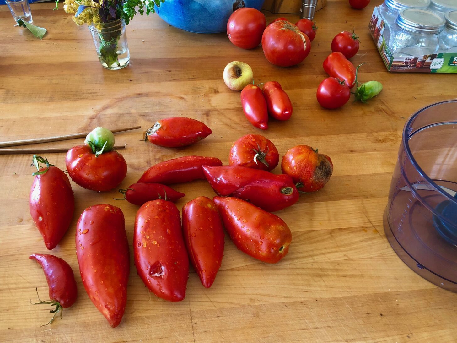 一堆看起来很美味的自制西红柿放在砧板上，周围是食品加工工具。